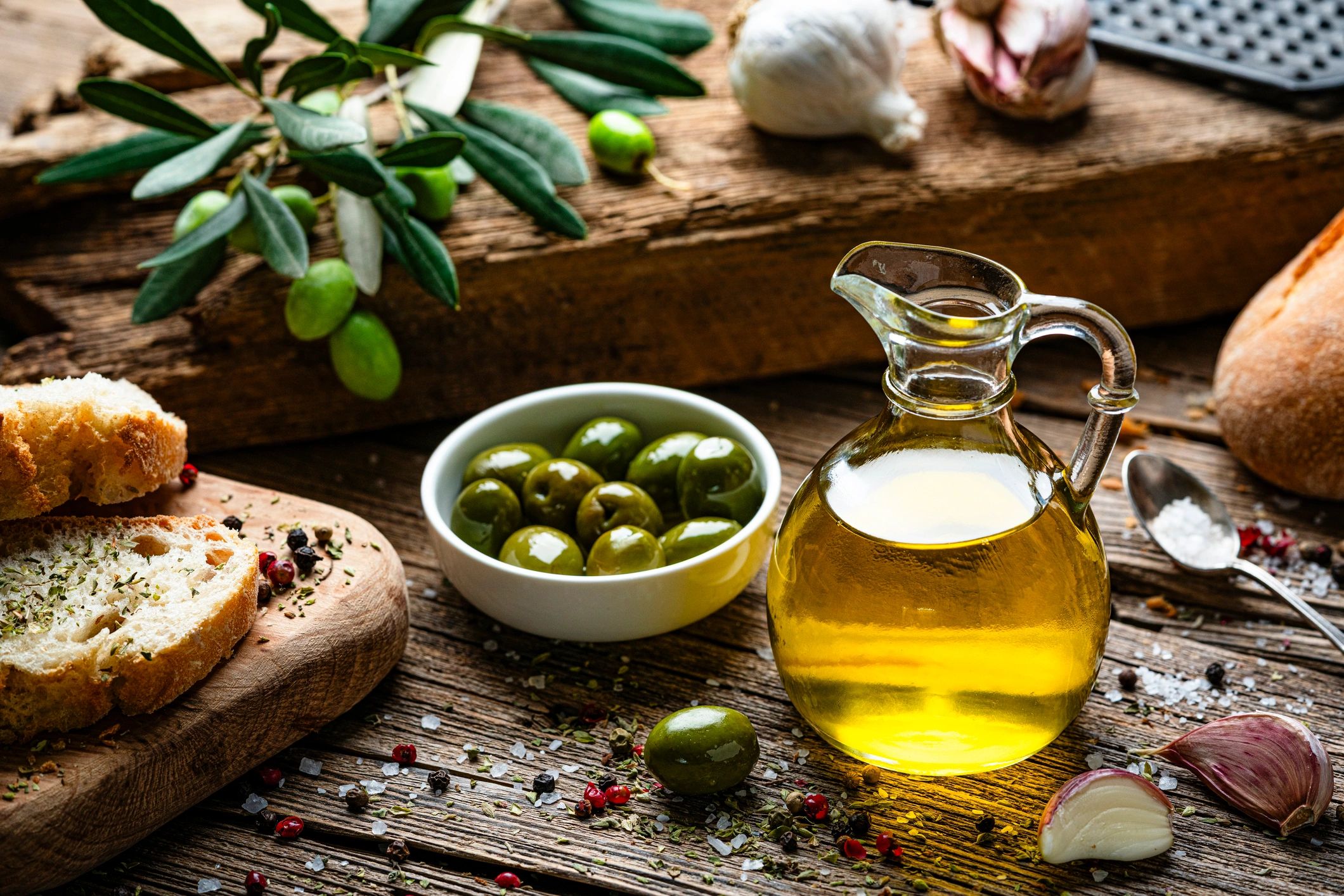 Extra virgin olive oil and olives on a rustic table